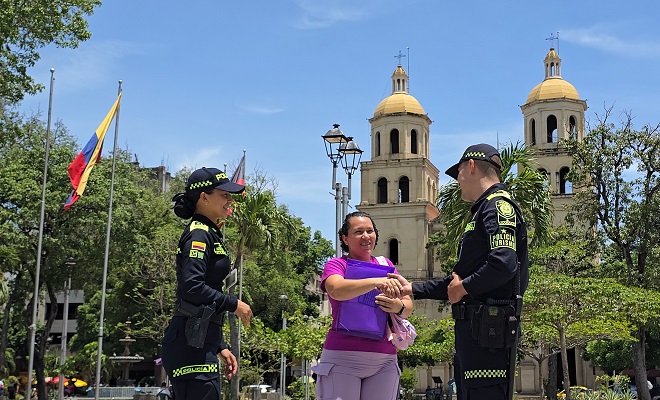 Dos polic&iacute;as de turismo dando indicaciones una mujer en un parque