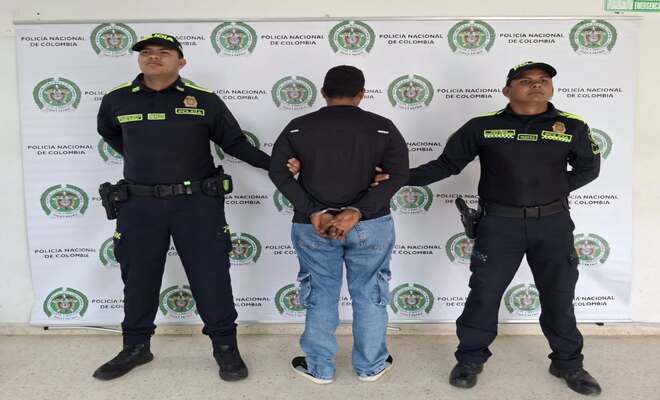 Dos uniformados custodian a un hombre señalado por presunto tráfico de moneda falsificada.