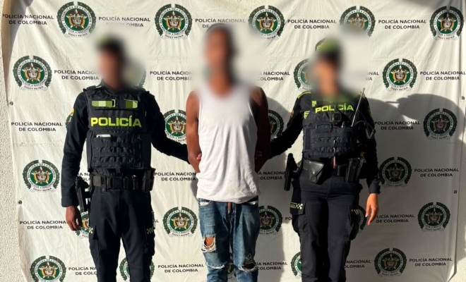 Dos funcionarios policiales junto a un ciudadano capturado frente a pendón institucional 