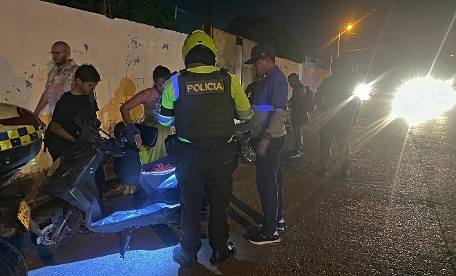 Funcionario policial de transito realizando verificación de documentación a un grupo de ciudadanos en vía publica 