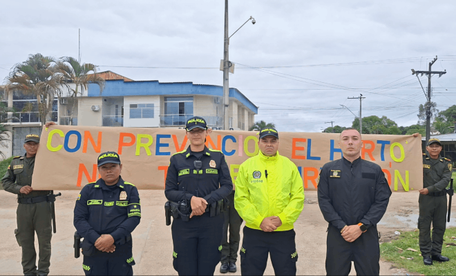 Cuatro policías en posición de entrevista mientras otros dos policías sostienen una cartelera con varios mensajes visibles