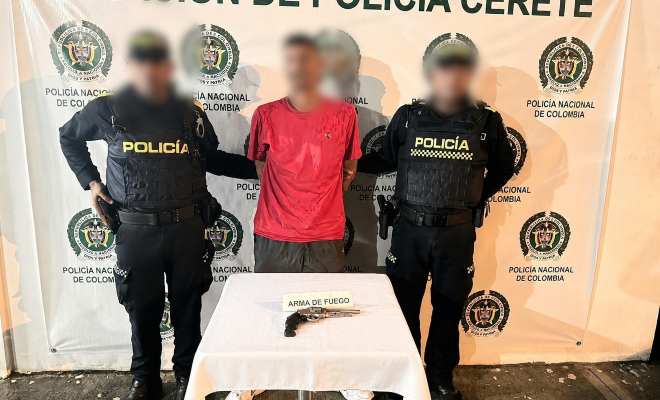 Dos funcionarios policiales con una persona capturada y un arma como elemento material probatorio