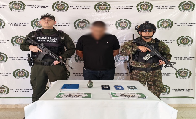 Policía y soldado custodiando un sujeto y los elementos incautados