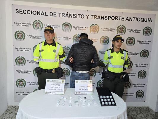 Dos polic&iacute;as de transito y transportes custodian a un capturado y esmeraldas incautadas