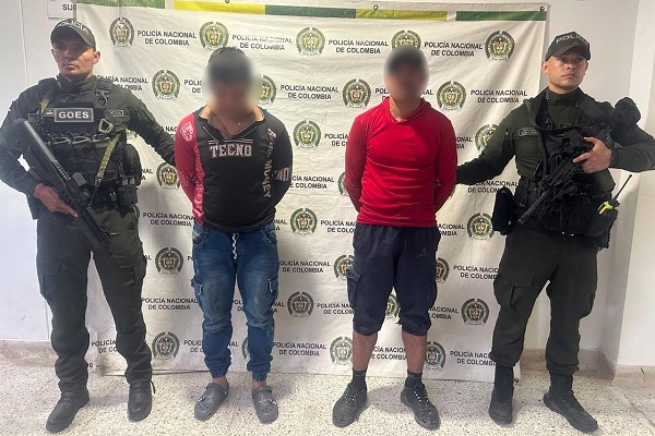 Dos uniformados custodian a dos hombres capturados