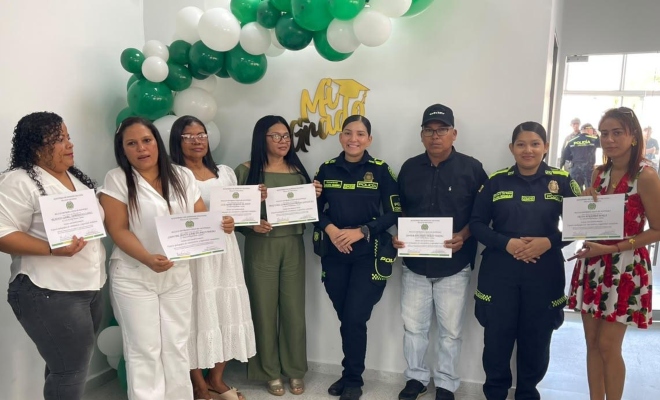 Grupo de personas que hicieron parte de los espacios pedagógicos junto a dos funcionarias policiales mostrando sus certificados 