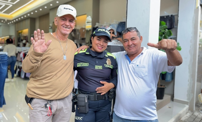 Dos ciudadanos junto a una funcionaria policial saludando en sector comercial