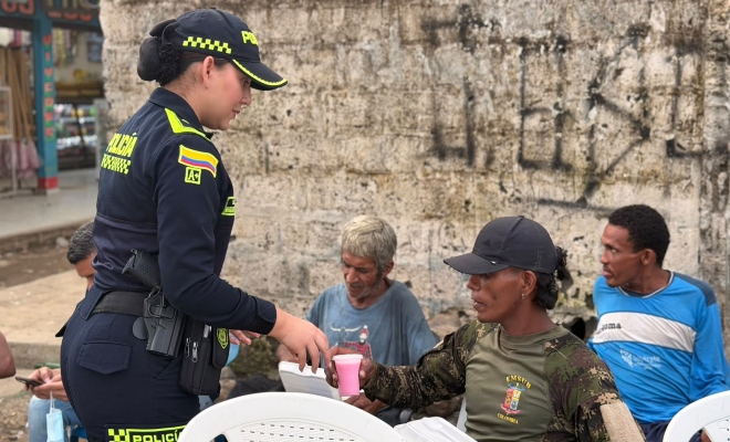 Funcionaria policial brindando desayuno a tres ciudadanos en actividades de iniciativa “Nadie Invisible”