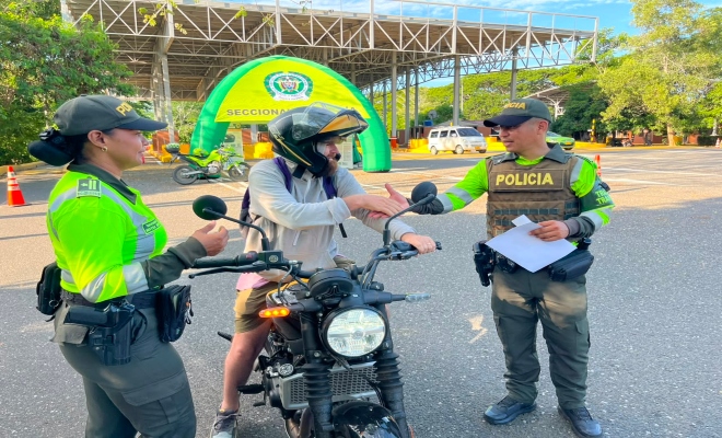 dos uniformados adscrito a la seccional de transito y transporte con un ciudadano en su vehículo brindando recomendaciones sobre seguridad vial  
