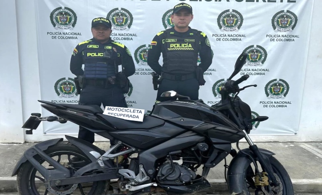 Dos funcionarios policiales con una  motocicleta frente a pend&oacute;n institucional 