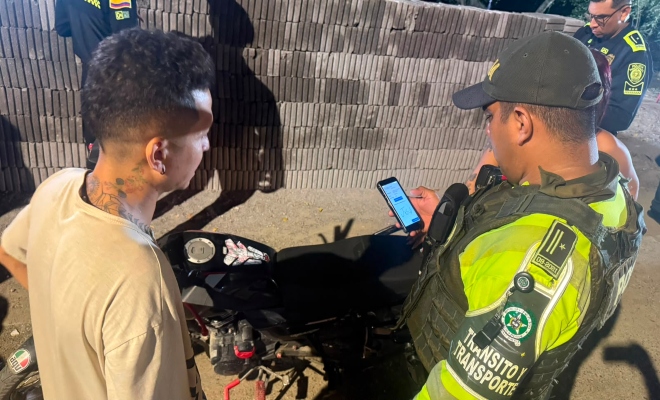 Funcionario policial de la dirección de transito y transporte realizando consulta de antecedentes a una motocicleta