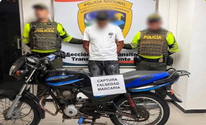 Dos funcionarios policiales de transito y transporte junto a un ciudadano capturado, frente a ellos una motocicleta incautada