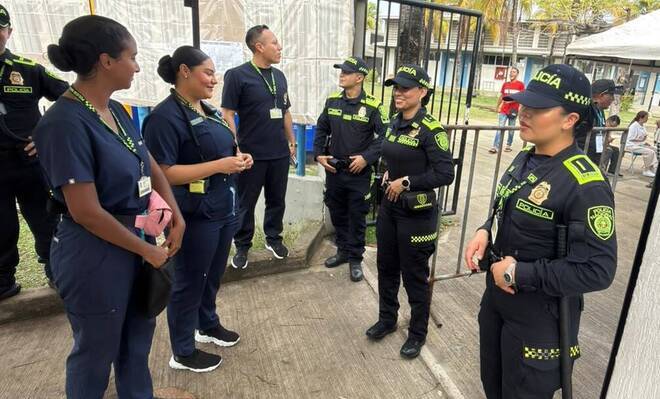 personal de sanidad se acerca a un grupo de uniformados que cuidan los puestos de votacion