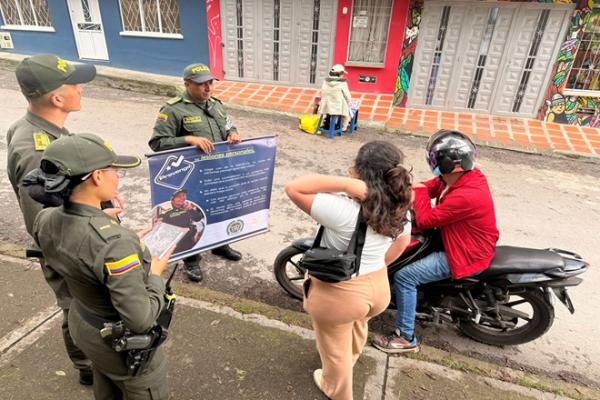 tres policias haciendo cama&ntilde;as de prevenci&oacute;n frente a una persona en su motocicleta y una ciudadana 