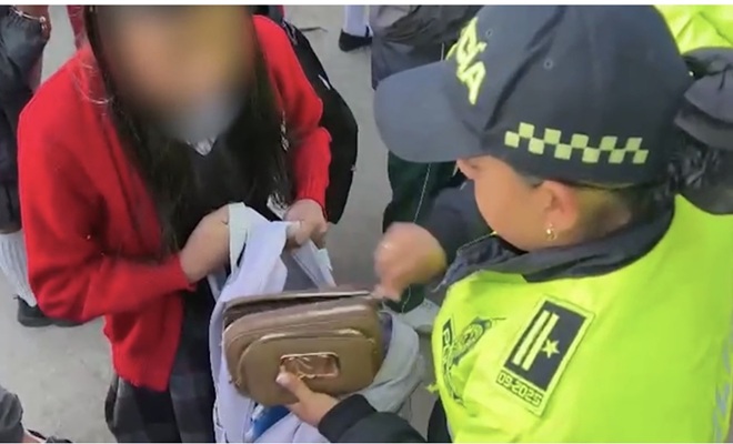 una policía haciendo un registro a un morral a un colegio 