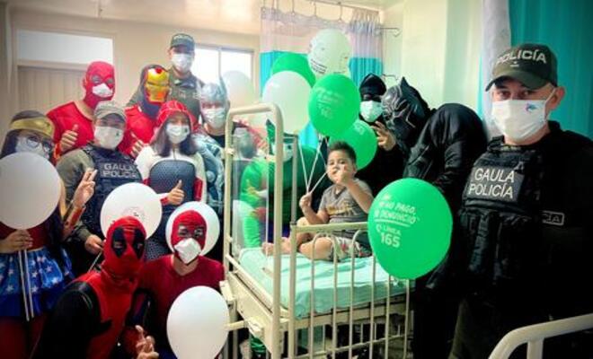 Personajes y policías acompañan a niño hospitalizado durante actividad recreativa.