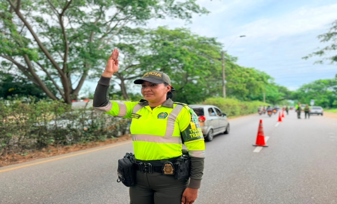un policía de transito saludando a la comunidad y realizando control del trafico 