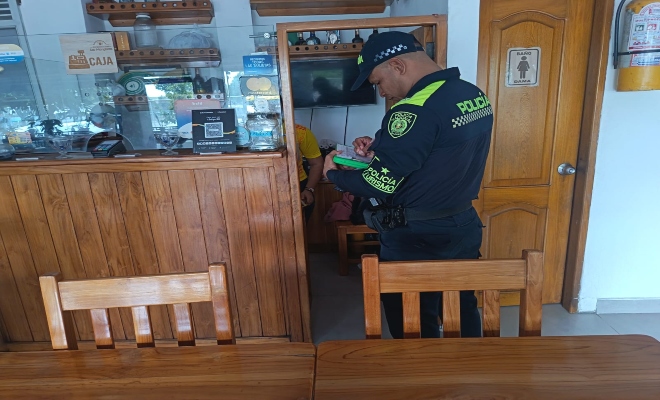 un uniformado de la policía nacional verificando establecimiento abierto al publico 