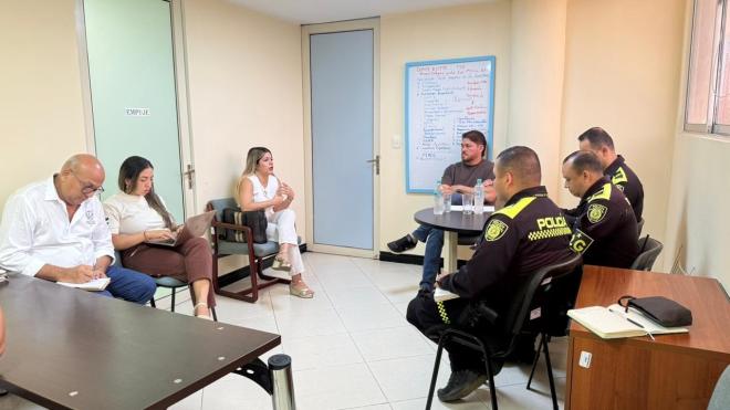un uniformado con varias personas en una mesa redonda dialogando