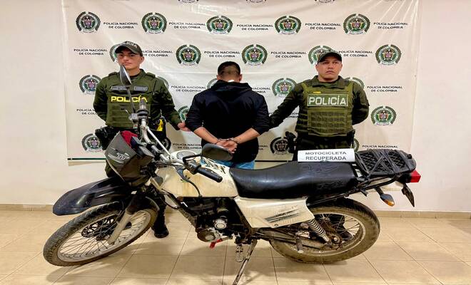 Un hombre capturado esposado dando la espalda con dos policías en cada lado respectivamente 