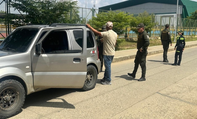 Un policía solicitando antecedentes y tres policías prestando seguridad 