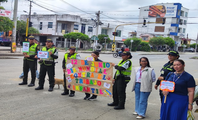 cuatro uniformados  y tres ciudadanas en un semáforo mostrando una cartelera Día Internacional Contra el Trabajo Infantil