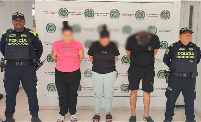 Dos polic&iacute;as sostienen a tres capturados en flagrancia.