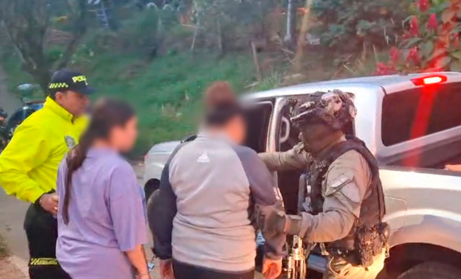 Dos Policías realizan el desplazamiento de dos capturados, hacía camioneta.