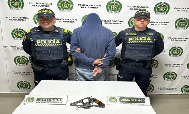 dos polic&iacute;as, un capturado, un arma de fuego, una mesa 