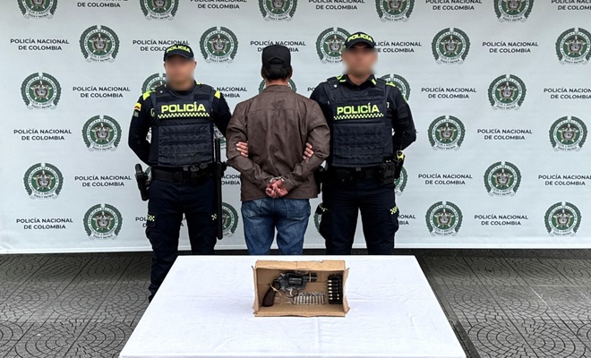 dos policías, un capturado, una mesa y un arma de fuego incautada 