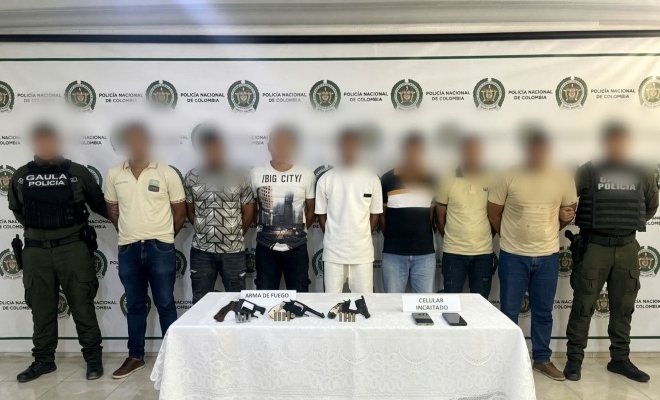 Dos funcionarios del grupo GAULA policía con siete ciudadanos capturados, frente a ellos tres armas de fuego y dos celulares  