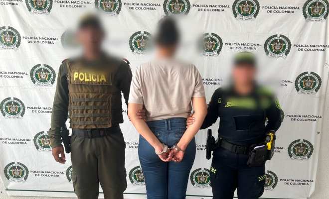 funcionarios policiales con una ciudadana capturada frente a pendón institucional