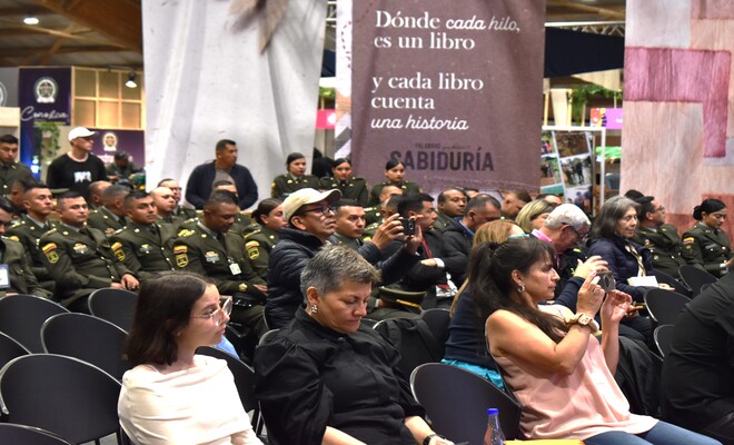 Personas no uniformadas y uniformados sentados en sillas viendo el lanzamiento de los libros