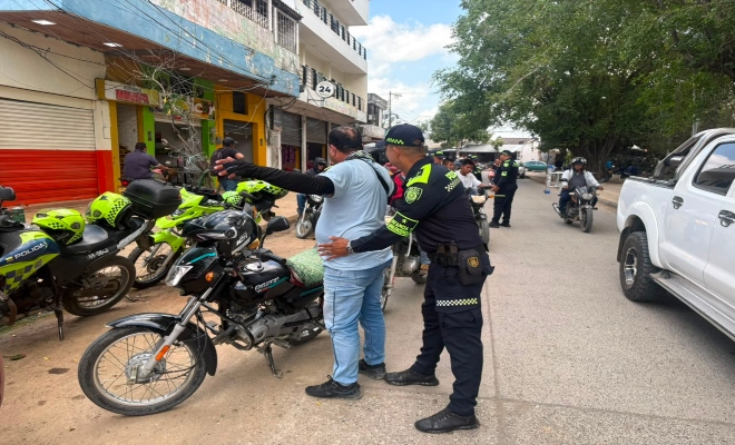un uniformado de la Policía nacional realizando registro a personas 