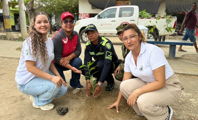 Un funcionario policial sembrando un árbol en compañía de la comunidad