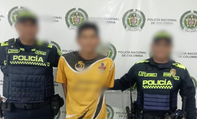 Dos funcionarios policiales con un ciudadano capturado con camiseta color amarillo