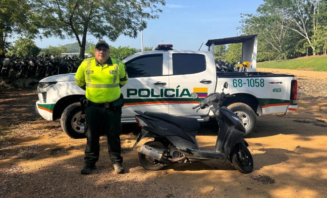 Funcionario policial de transito y transporte junto a una motocicleta recuperada en espacio abierto detr&aacute;s de este una camioneta de la Polic&iacute;a Nacional