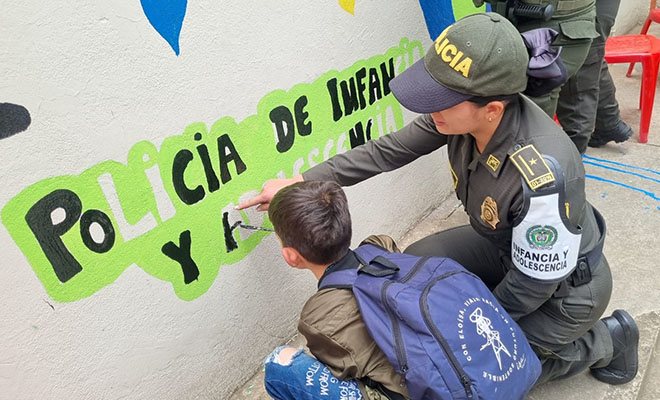 Mujer policía con un niño pintando un mural