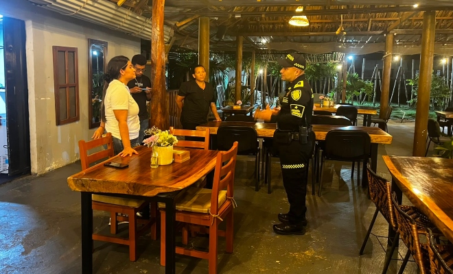 Funcionario policial brindando recomendaciones a tres ciudadanos en sector comercial