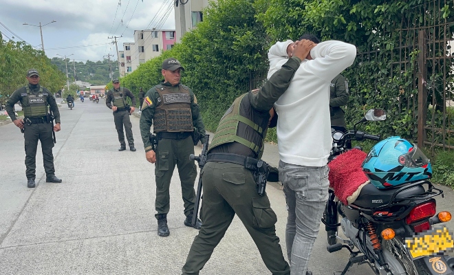 Un grupo de funcionarios policiales realizando un registro a persona a un ciudadano junto a una motocicleta