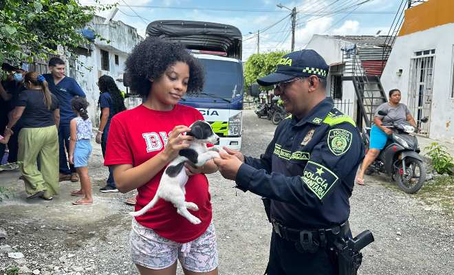 Funcionario policial junto a una ciudadano con un cachorro sonriendo 