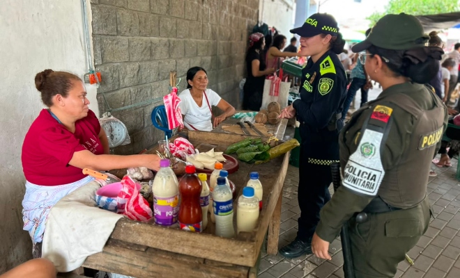 Dos funcionarias policiales saludando a dos ciudadanas en la plaza de mercado