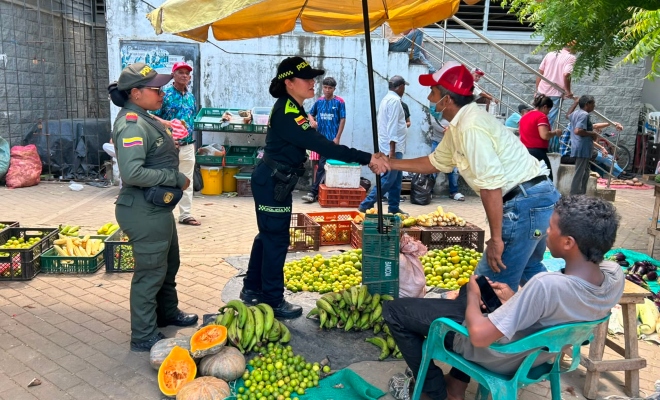 Dos funcionarias policiales saludando a dos ciudadanos en la plaza de mercado