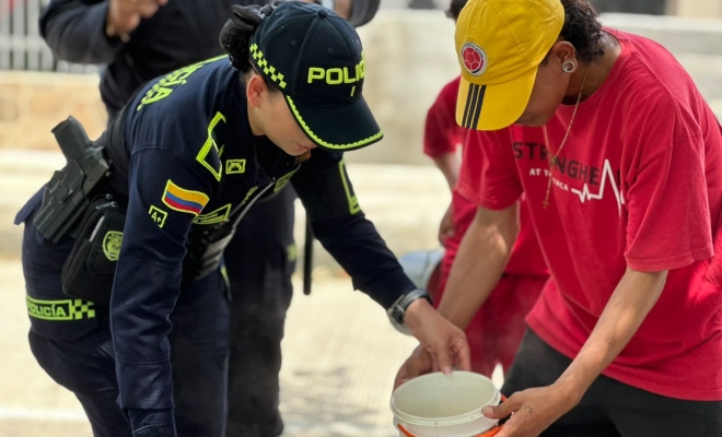 Funcionaria policial junto a joven barrista preparando la olla comunitaria