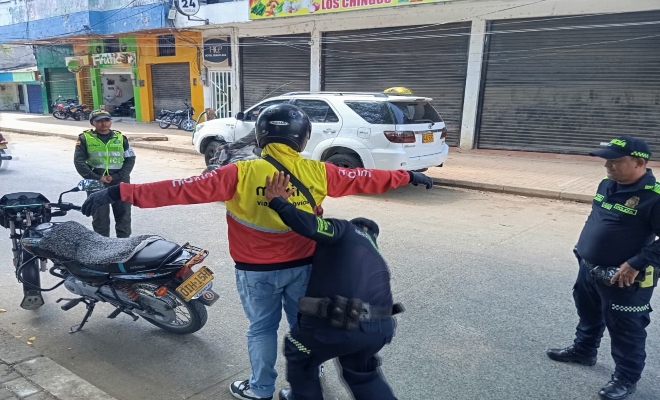 un policia practicando registro a un ciudadano y dos prestando seguridad 