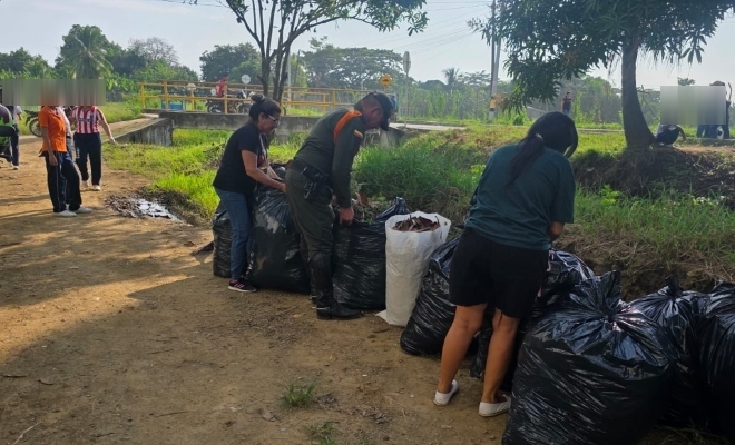 Funcionario policial realizando actividad de limpieza y recuperación de espacios junto a dos ciudadanas 