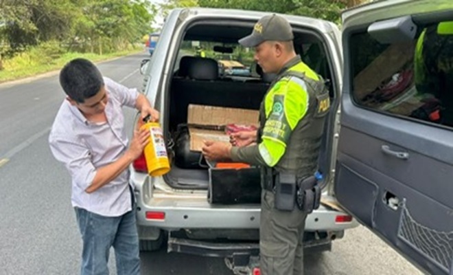 Un funcionario policial de tránsito revisando kit de carretera a un vehiculo junto con un ciudadano
