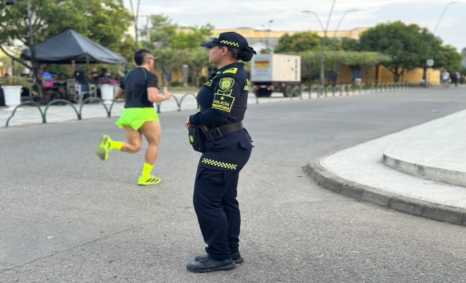una funcionaria de la Policía Nacional prestando seguridad a los corredores de la carrera que se llevó  acabo en el municipio de cereté
