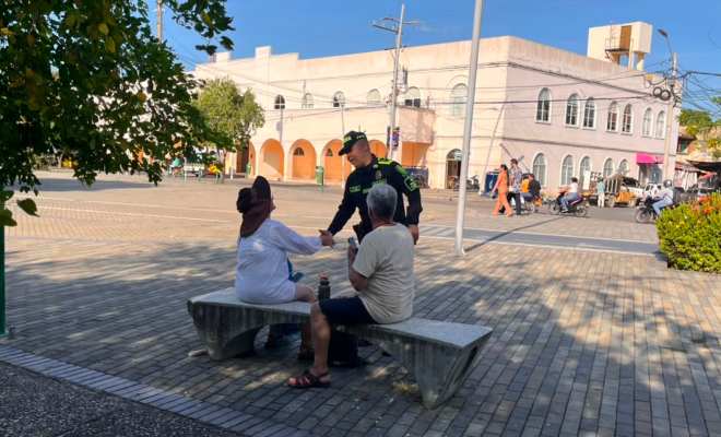 Funcionario policial saludando a dos ciudadanos e impartiéndoles recomendaciones de seguridad