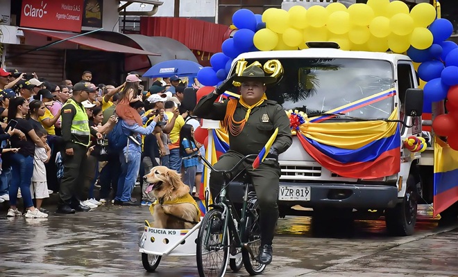 Un canino junto a su guía desfilando